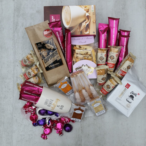 Assorted items - coffee, bicuits, rusks, chocoloate, mug arranged beautifully in a hamper